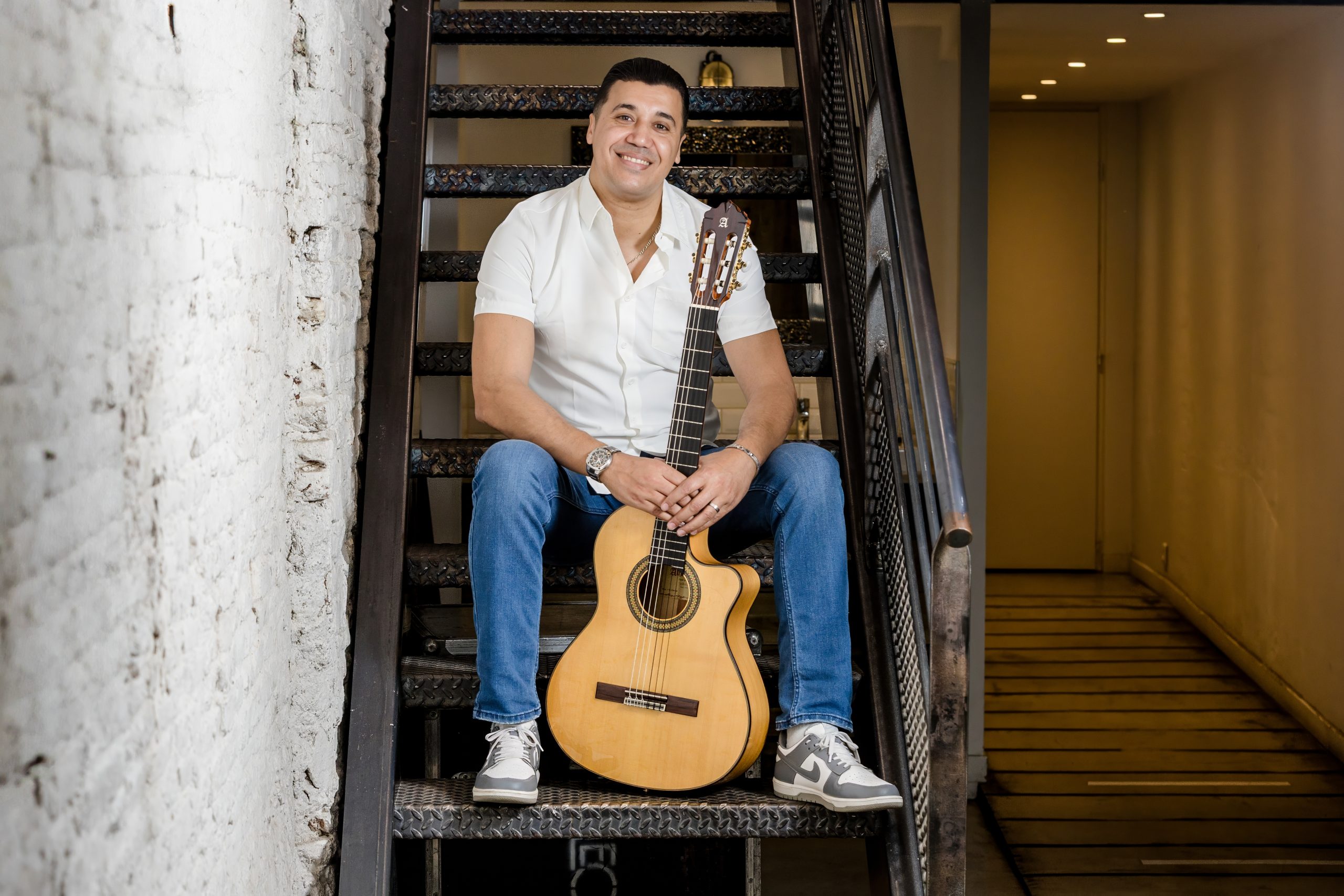 Amine Belayachi assis dans un escalier avec sa guitare
